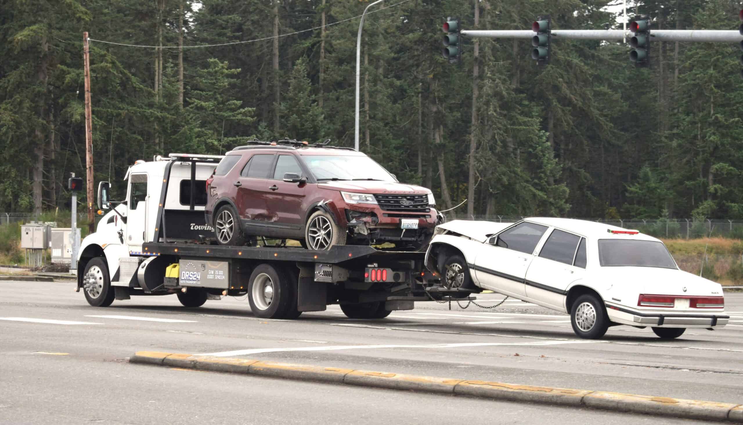 image of a tow truck towing 2 cars on the road for emergency towing