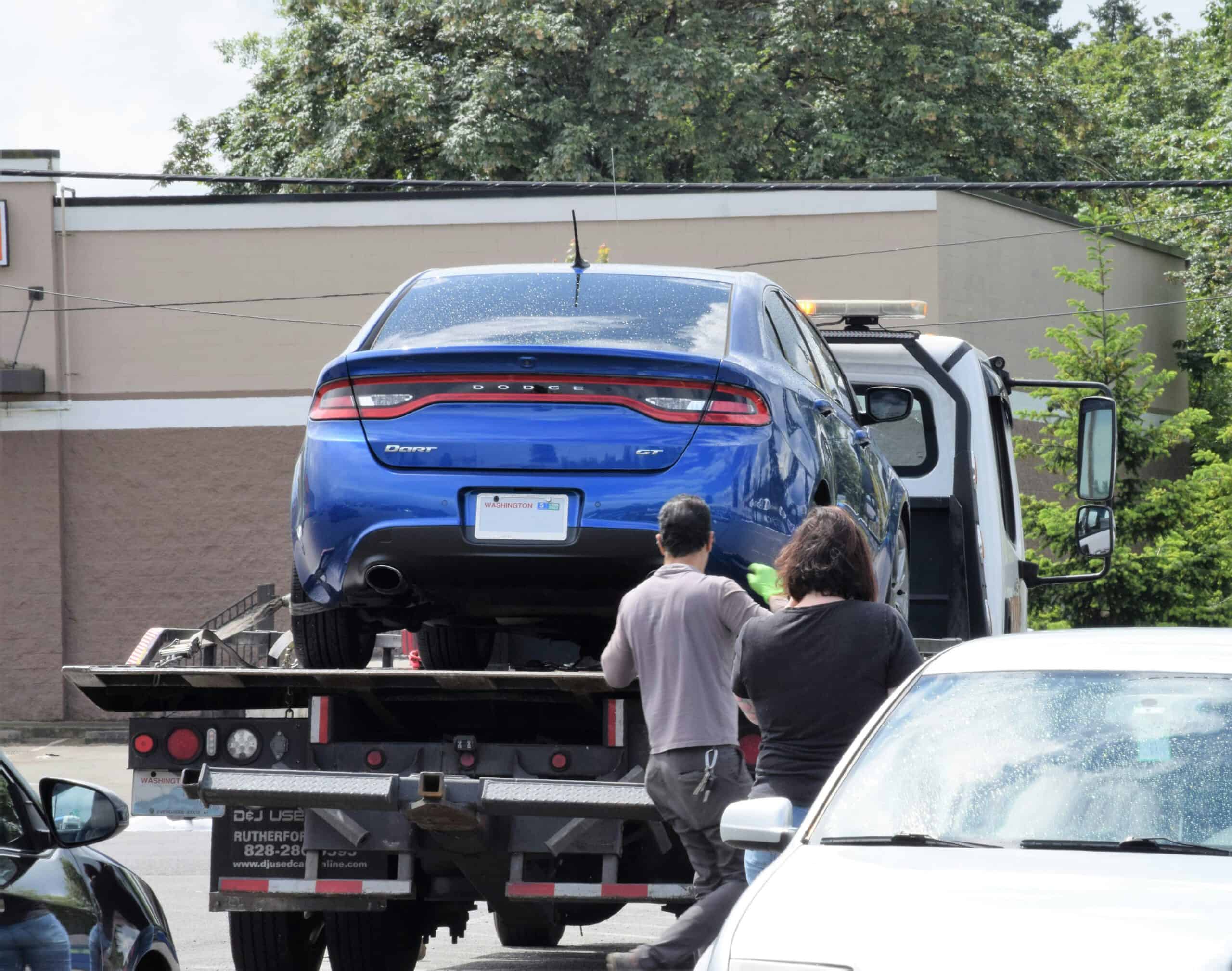 image of a blue car about to towed by tow truck